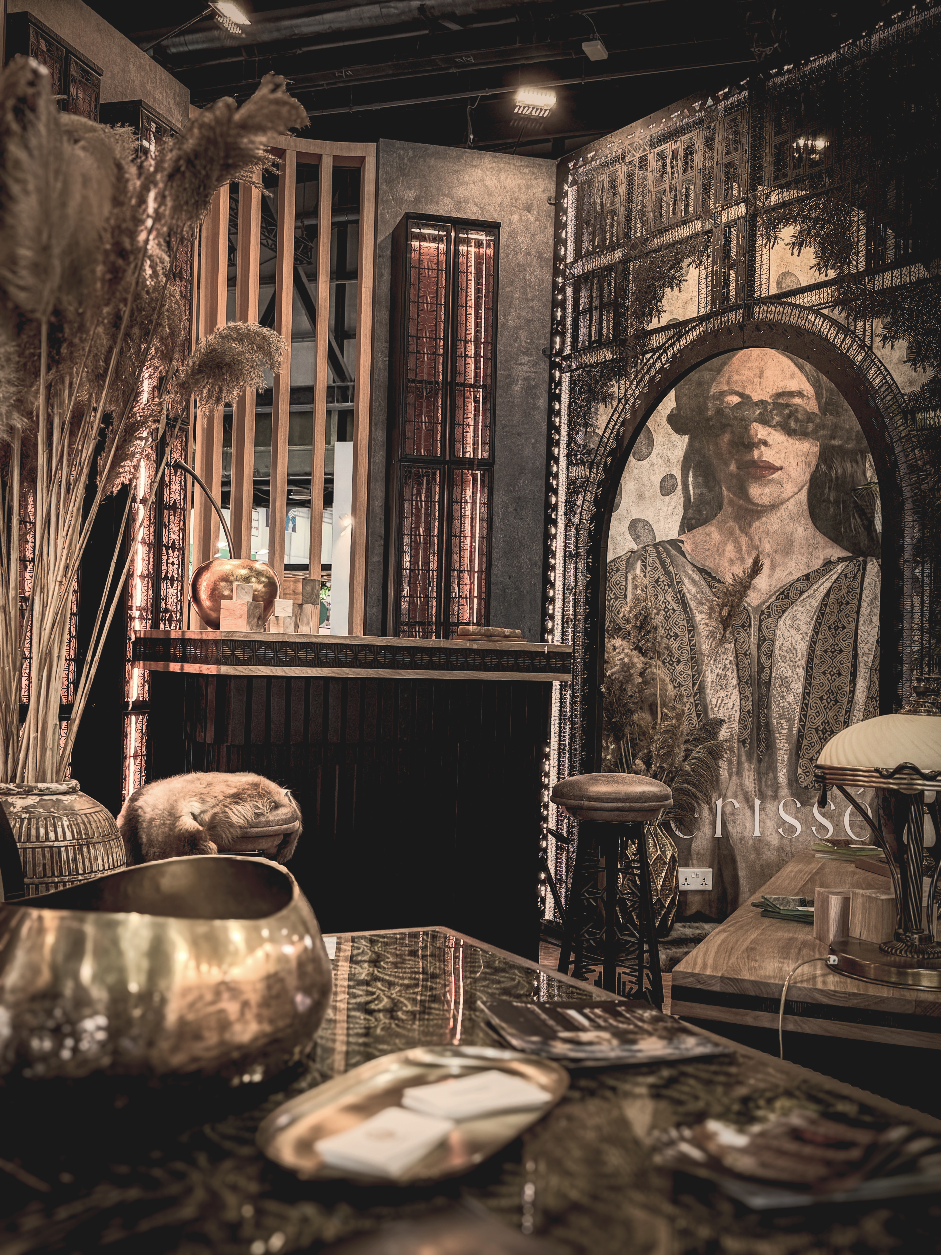 Moody bar interior with a dark counter, layered decorative screens, and a large mural portrait