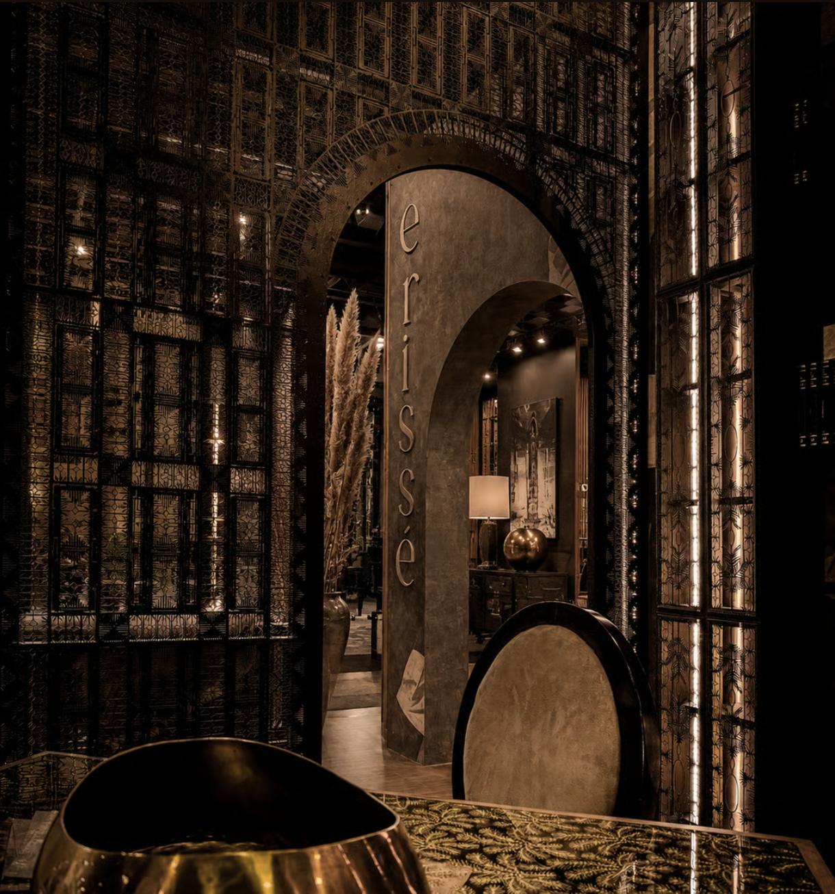 Moody bar interior with a dark counter, layered decorative screens, and a large mural portrait